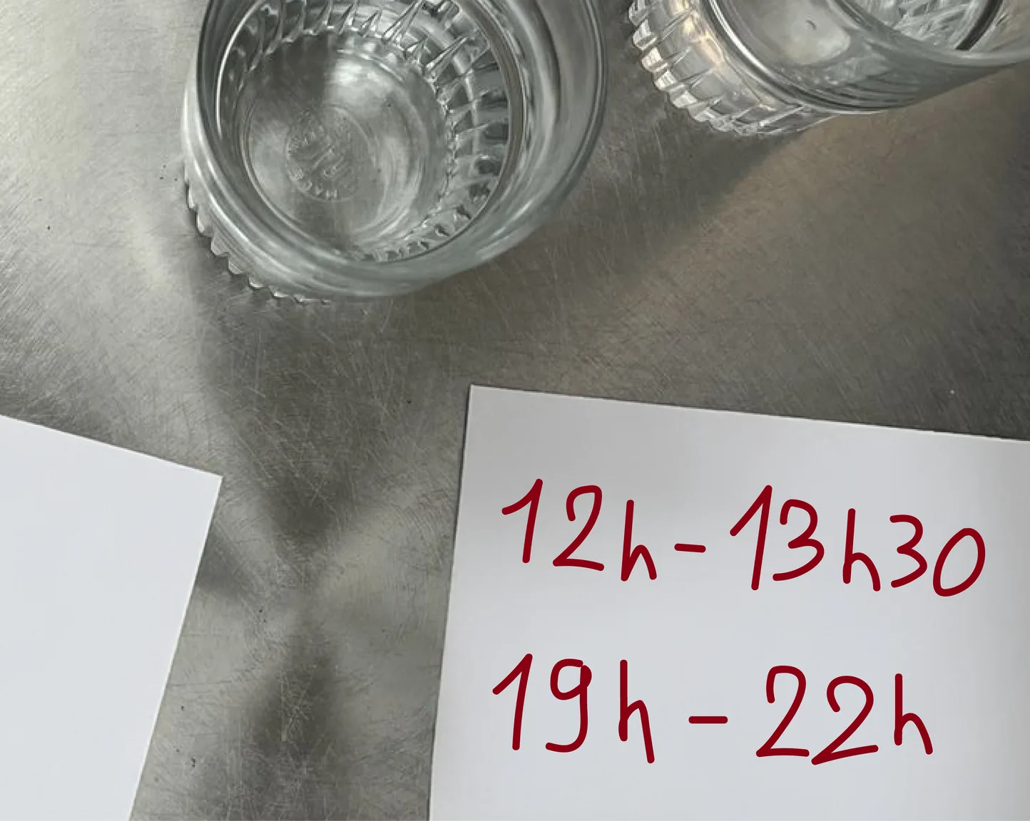 Deux verres sur une table en inox, à côté d'un papier